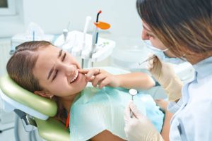 Girl sitting at dental chair with open mouth during oral check up while doctor. Visiting dentist office. Dentistry concept